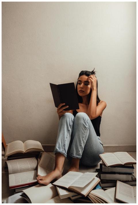 A young woman sitting indoors, deeply focused on r