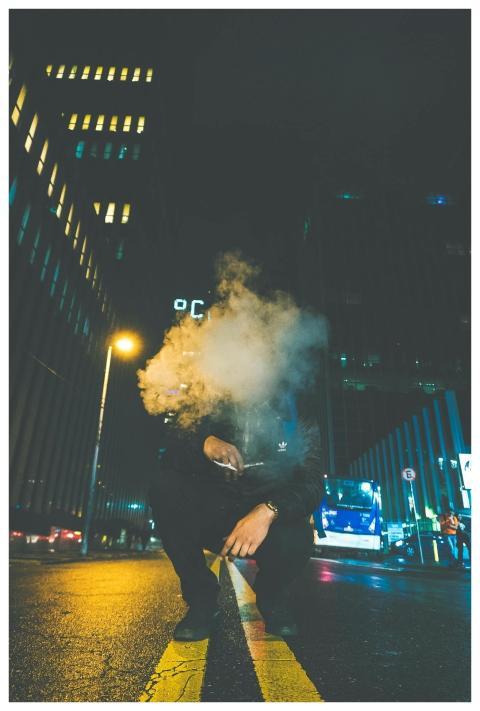 A man surrounded by smoke on a city street at nigh