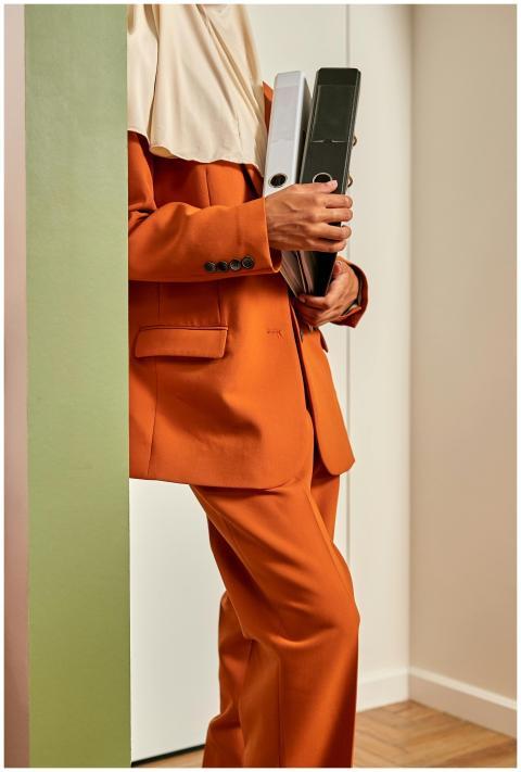 Businesswoman in orange suit holding documents wea