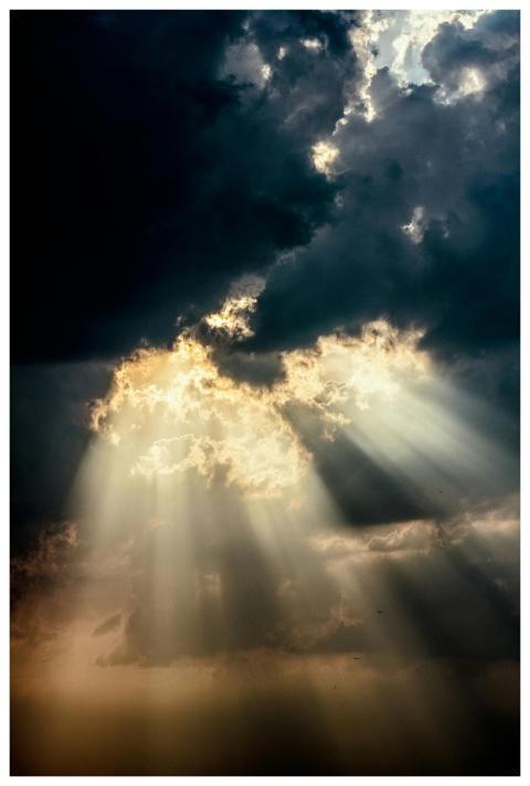 Sun rays piercing through dark clouds create a dra