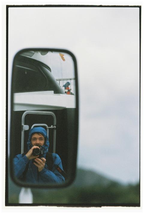 Man in blue jacket capturing photo reflection in v