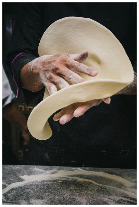 Close-up of chef tossing pizza dough in a kitchen,