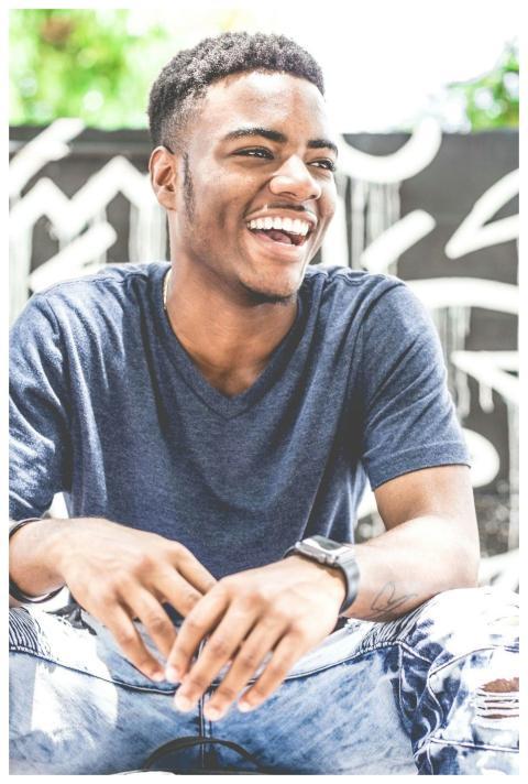 Happy young man sitting outdoors with a bright smi