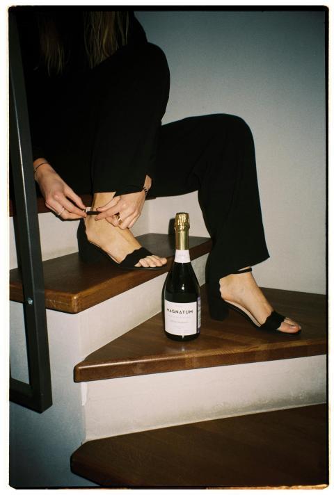 A person adjusts high heels while sitting on stair