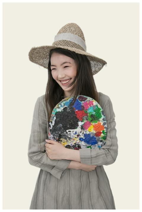 Smiling artist holding a colorful paint palette, w