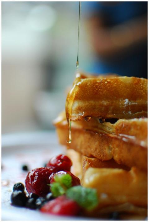 Syrup drips onto stacked waffles with fresh berrie