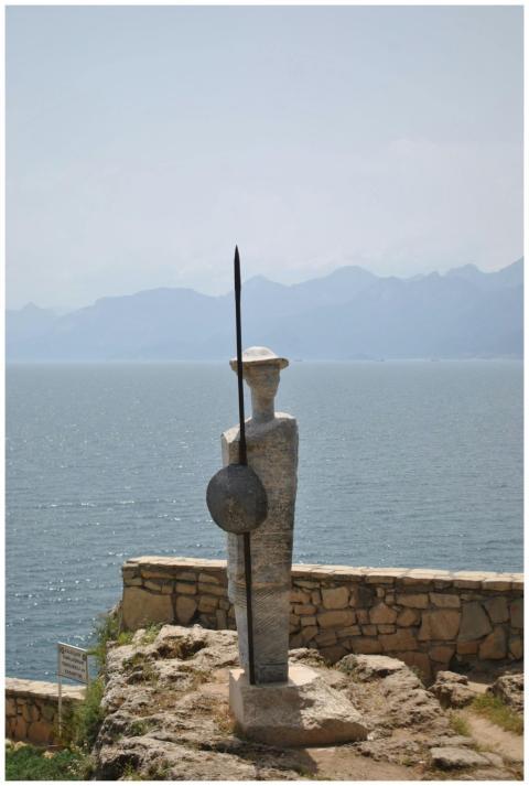 Stone warrior statue overlooking the sea with dist