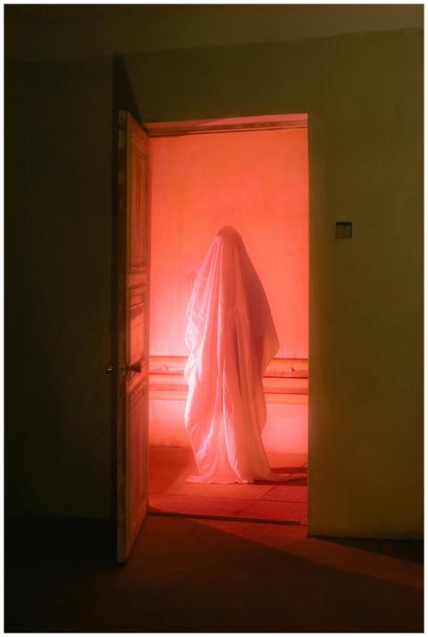 A ghostly figure in a white sheet stands in a room