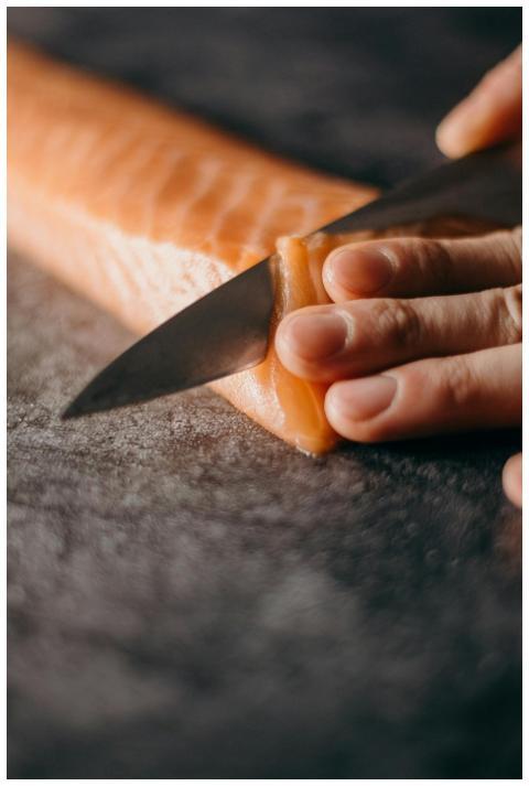 Close-up of hands skillfully slicing fresh salmon