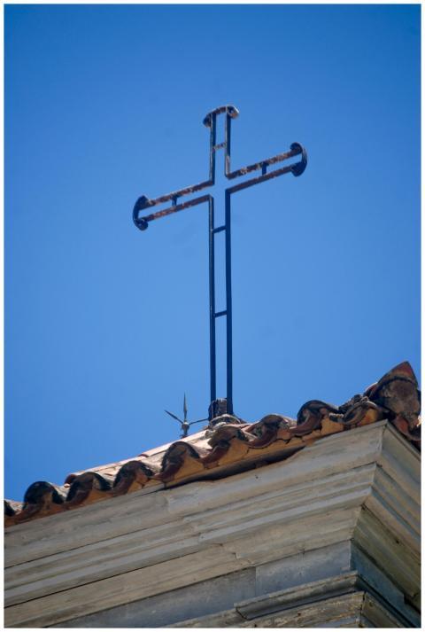 Metal cross on a colonial church roof against a cl