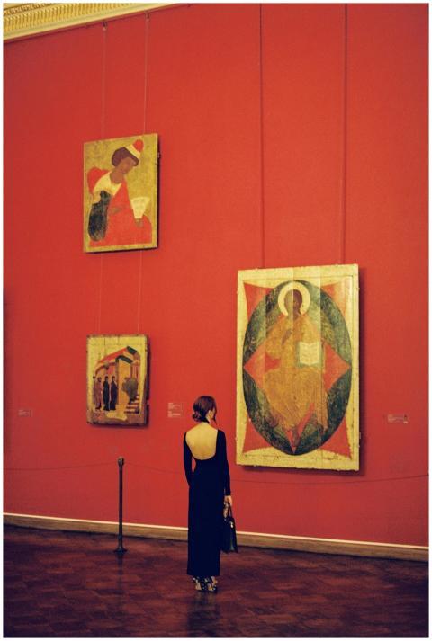 A woman in a black dress observes paintings in a r