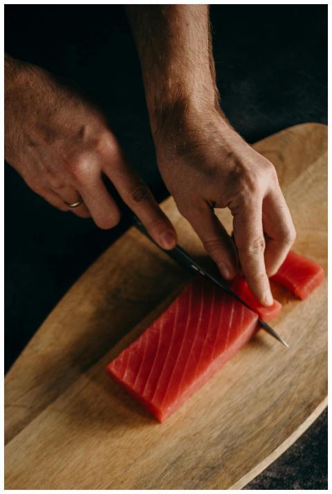 A person skillfully slices fresh tuna sashimi on a