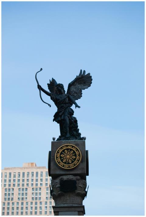 A black sculpture of an archer with wings on a ped