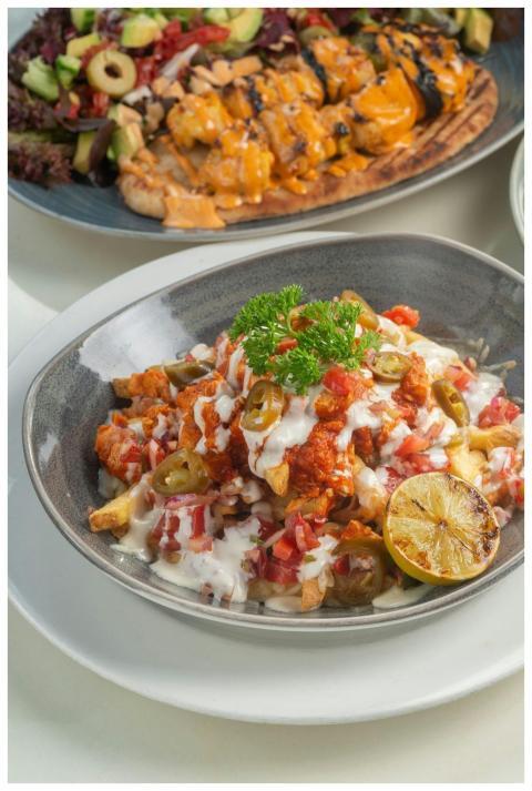 Loaded fries with toppings, garnished with lime an