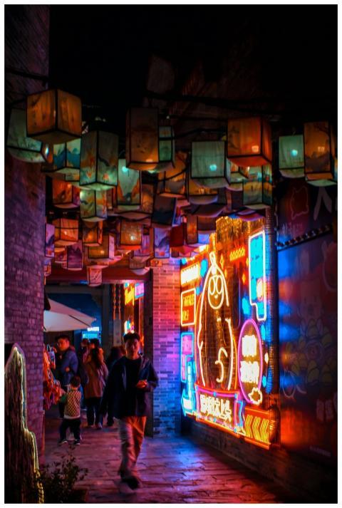 Colorful neon signs light up a lively alleyway wit