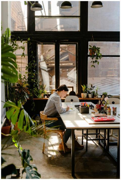 A woman artist focused on her work in a sunlit stu