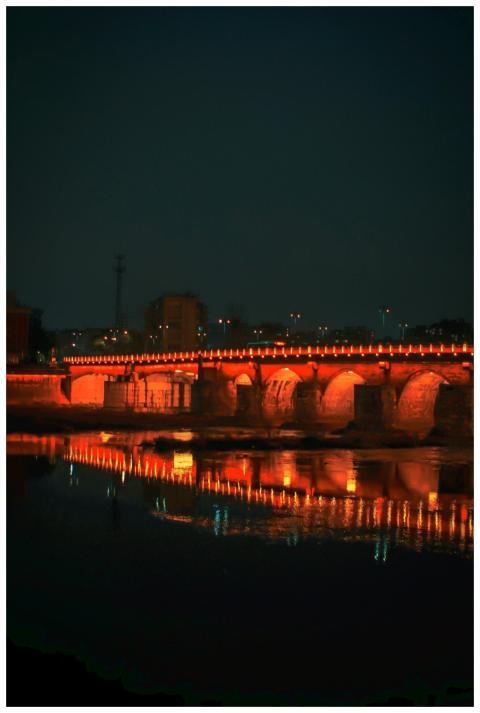 A beautifully lit bridge reflecting on the calm wa
