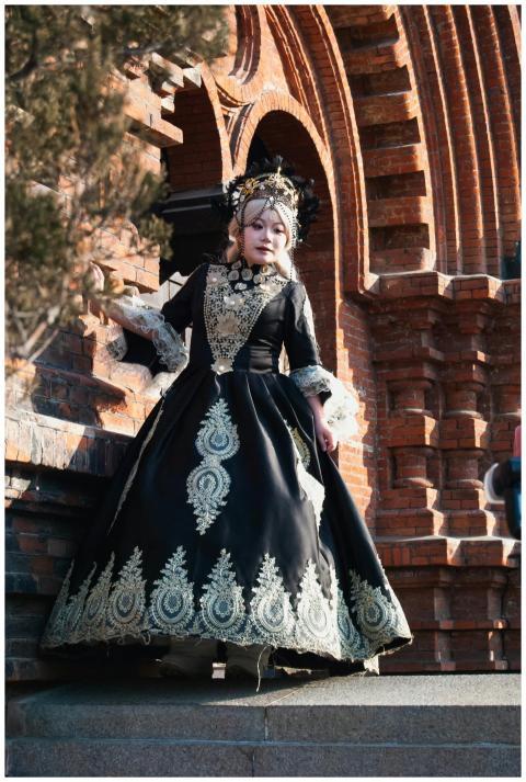 A woman in a gothic gown poses by intricate red br
