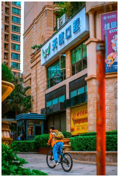 Person biking by modern building with vibrant sign