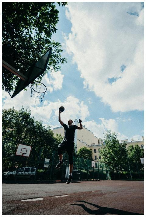 Action-packed shot of a man mid-air dunking a bask