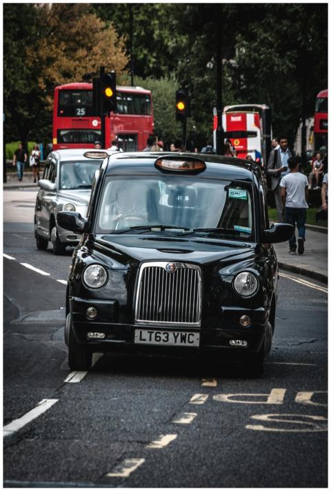 Classic black taxi navigating a bustling London st