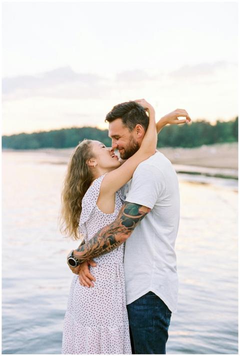 A loving couple embraces by a tranquil lake with a