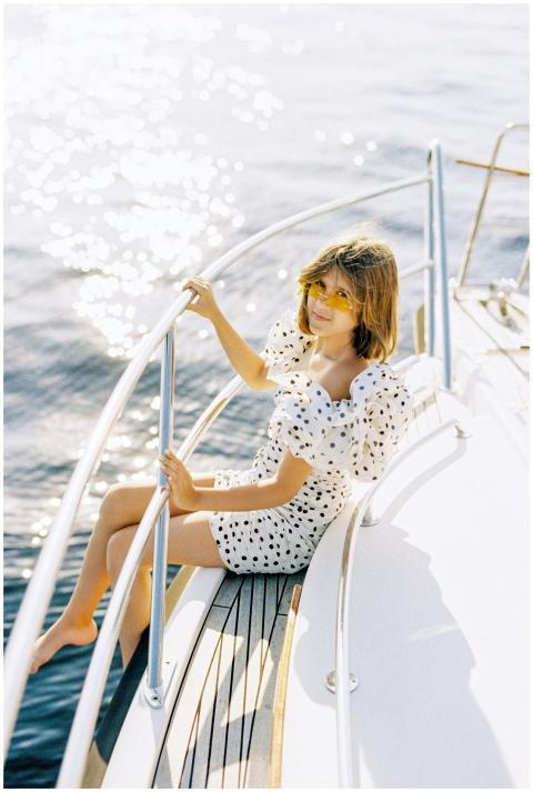 A stylish woman in a dotted dress relaxes on a yac