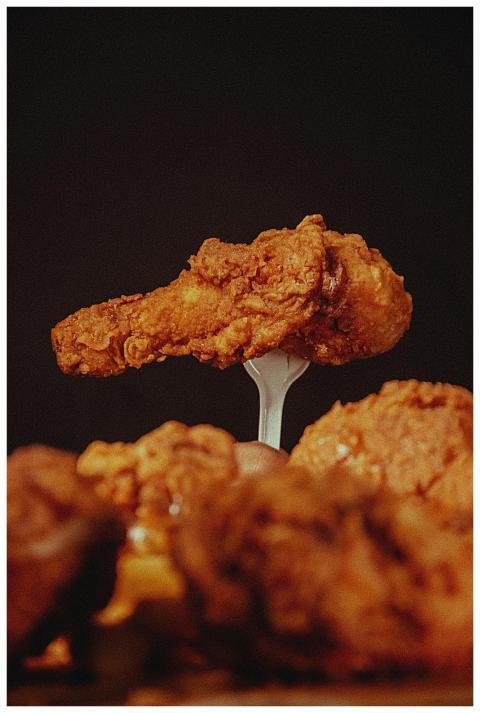 Close-up of a crispy fried chicken wing held aloft