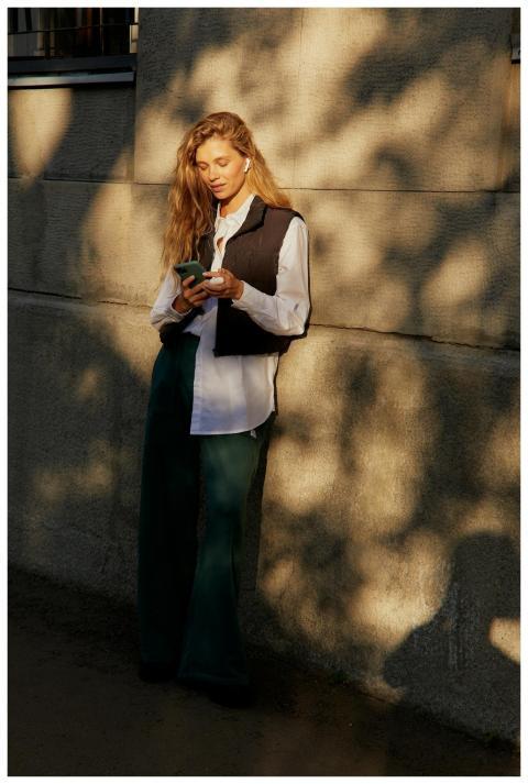 A stylish woman in the city using a smartphone, en