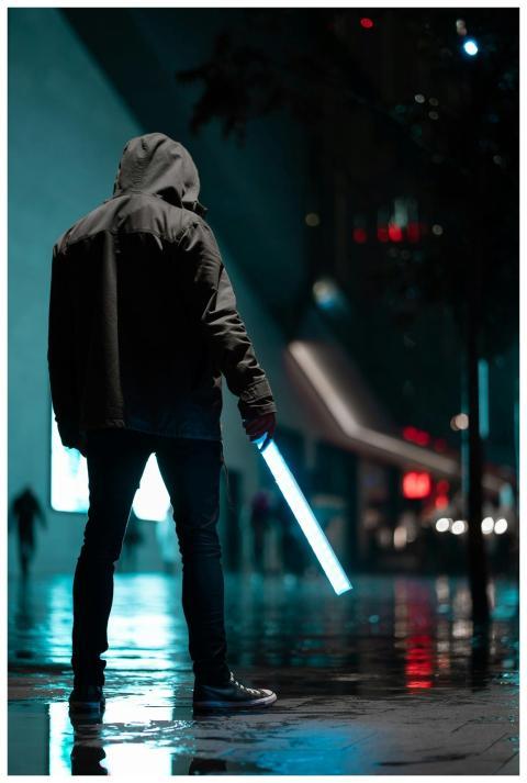 Silhouetted person in hoodie holding glowing light
