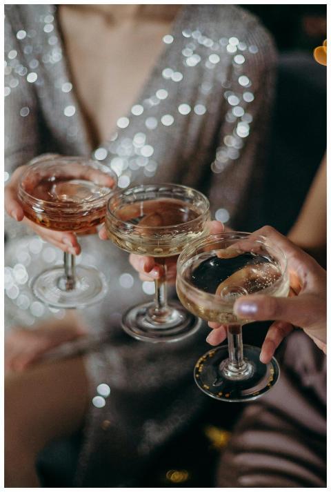 Three people clinking glasses filled with cocktail