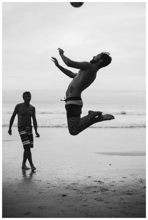 Dynamic shot of a shirtless man leaping to hit a s