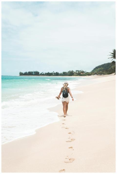 A woman with a backpack walks barefoot along a pri