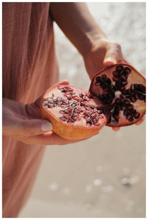 Close-up of hands holding a ripe pomegranate cut o