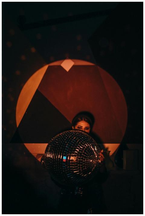 A stylish woman holding a disco ball, capturing th
