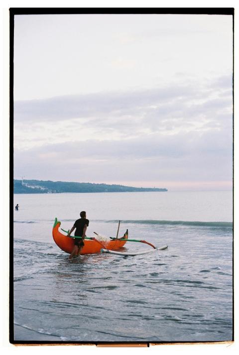 A man launching a traditional boat into the calm w