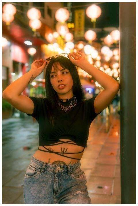 Stylish woman poses in vibrant night scene with ha