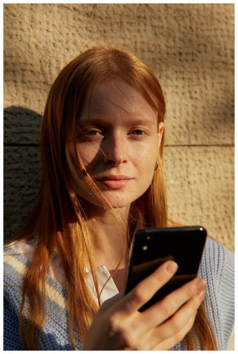 Young woman holding smartphone against a textured