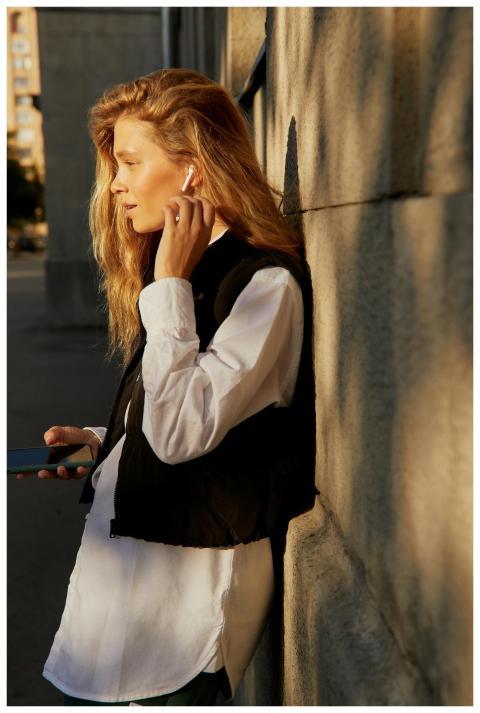 Stylish woman enjoying music with earphones on a s