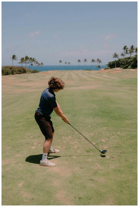 A golfer in mid-swing on a beautiful coastal golf