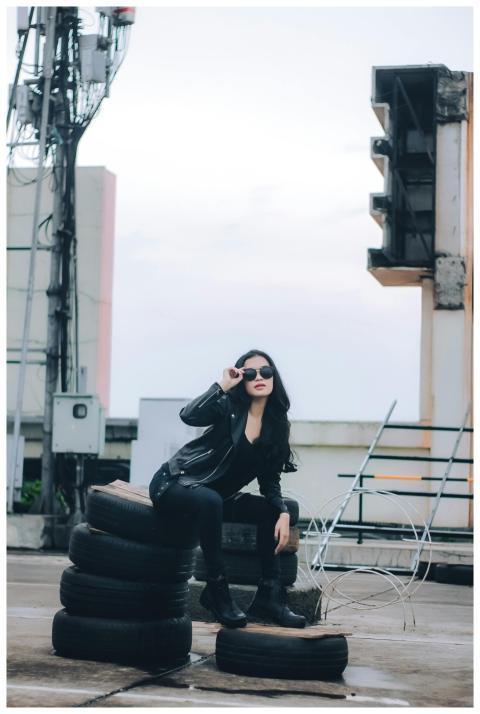 Chic woman in black outfit poses on rooftop with u