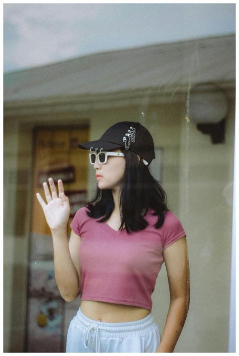 Stylish young woman in sunglasses posing behind gl