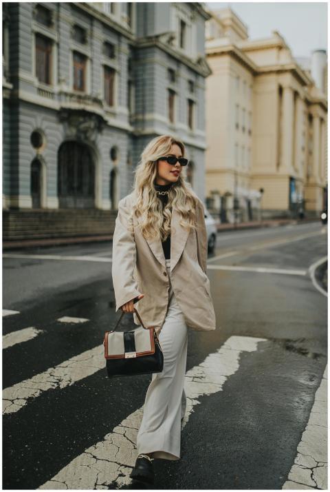 Stylish woman in a coat and sunglasses crossing th