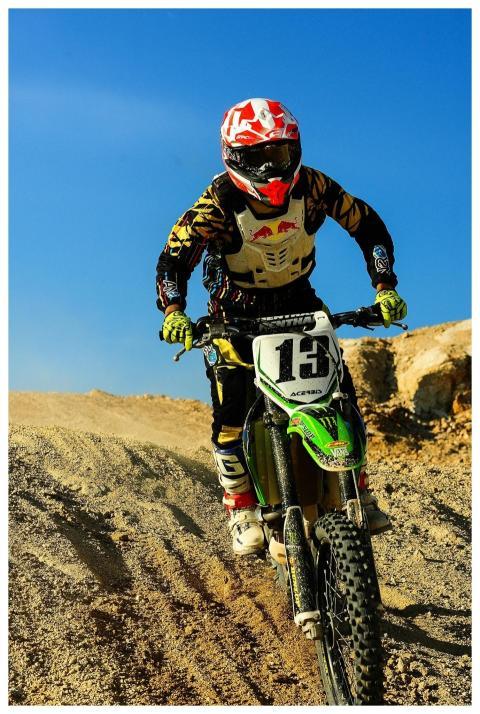 Motocross rider speeding on a dirt track under a c