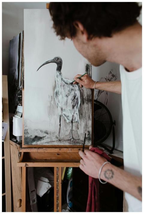 Side view of an artist painting an ibis in a creat