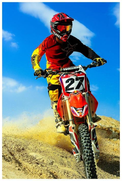 Motocross rider speeding on dirt track, showcasing