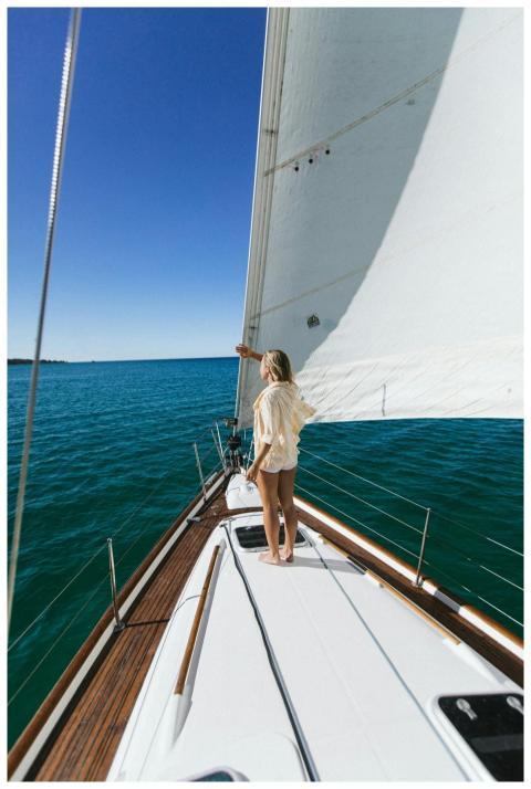 A woman standing on a yacht enjoying the clear blu