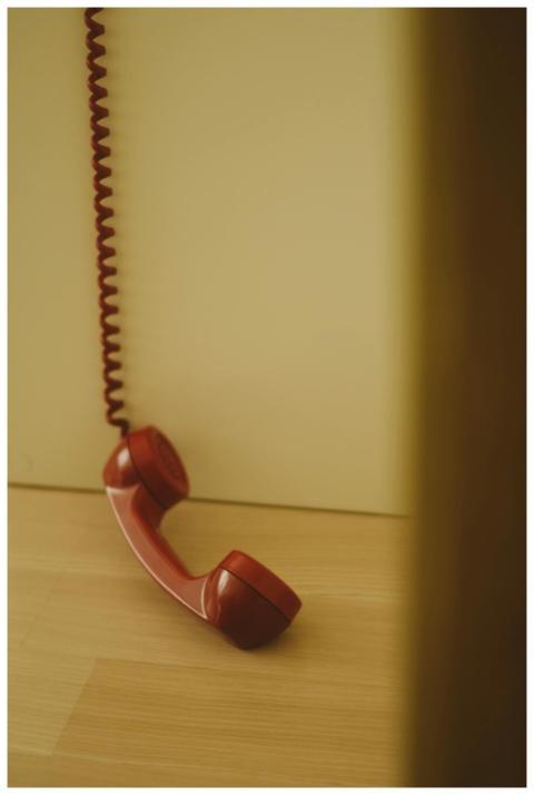 Close-up of a red vintage telephone handset restin