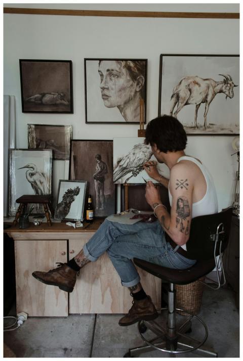 A young male artist painting in his studio, surrou