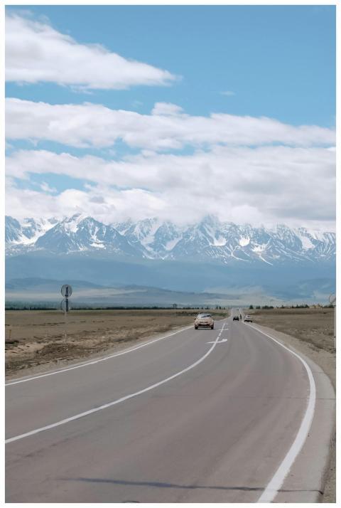 A winding highway leads toward stunning snow-cappe